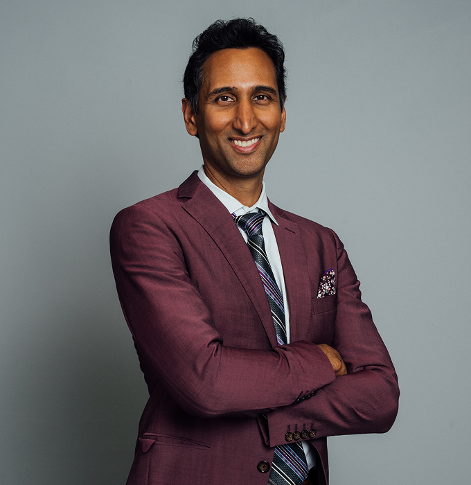 A portfolio shot of Dr. Surjit Rai wearing a maroon suit and black multicolored tie, smiling at the camera. - Doctor in Dallas, TX