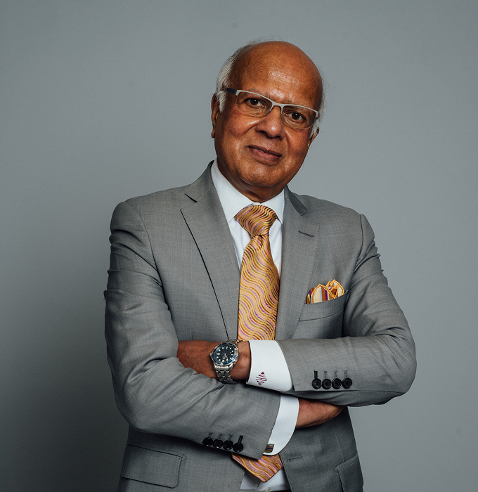 A portfolio shot of Dr. Vasdev Rai wearing a grey suit and mustard multicolored tie, smiling without teeth at the camera. - Doctor in Dallas, TX